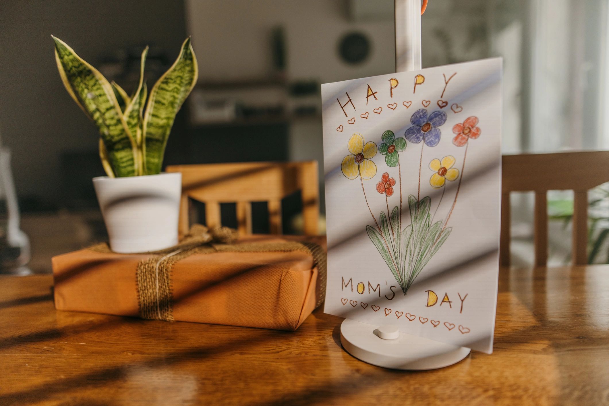 Gift box, potted plant and children's drawing arranged on a table
